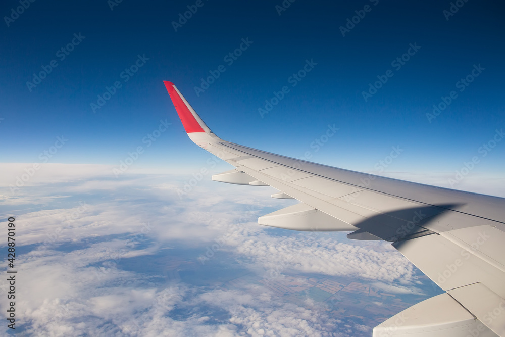 Airplane wing above white clouds. Selective focusing on the wing. The shadow on the wing of an airplane.