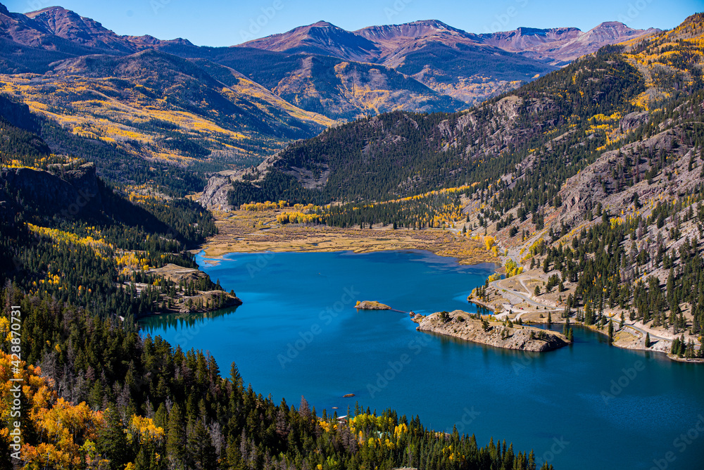 a bold blue lake surrounded by mountains and yellow aspen trees