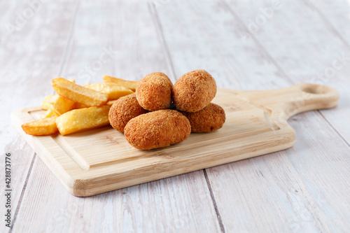 Homemade croquettes with chips on wood cutting board
