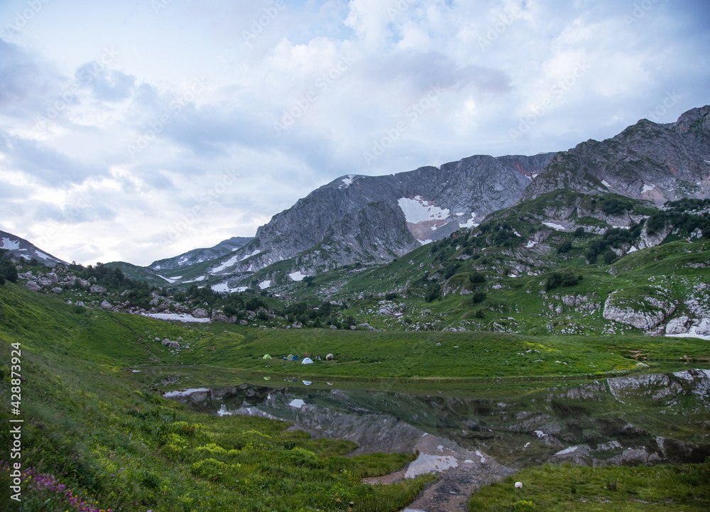 panoramic view of the mountain lake with tourist tents  a cloudy summer day. Adygea, Russia.