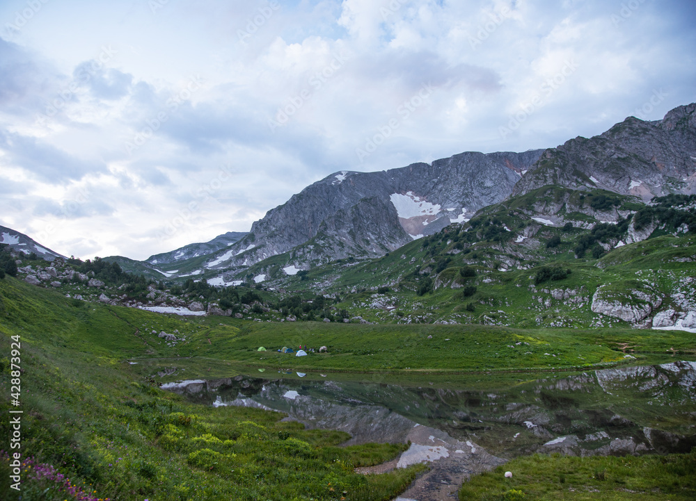 panoramic view of the mountain lake with tourist tents a cloudy summer day. Adygea, Russia. panoramic view of the mountain lake with tourist tents a cloudy summer day. Adygea, Russia.