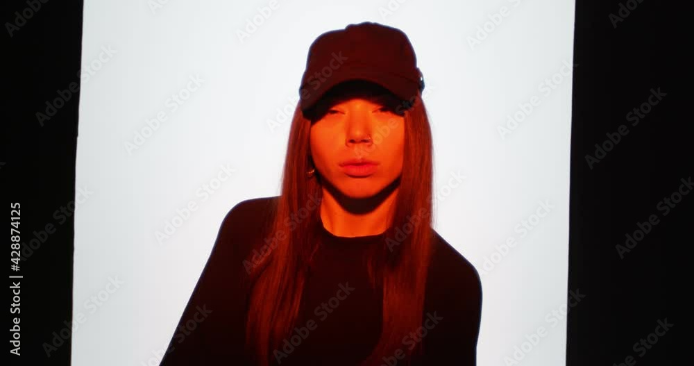Modern young hip hop girl in cap dancing in red studio light. Contemporary dance and youth rap culture Modern young hip hop girl in cap dancing in red studio light. Contemporary dance and youth rap culture