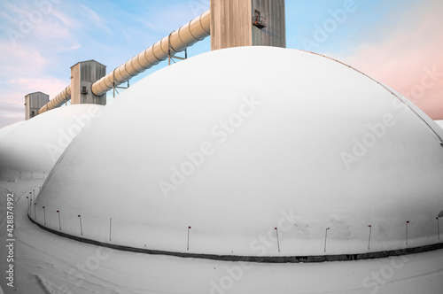 Dome-type warehouse for bulk cargo. Nearby there is a building where self-unloading industrial wagons - hoppers call in on railway tracks (rails). There they are unloaded, and then, the bulk cargo on 