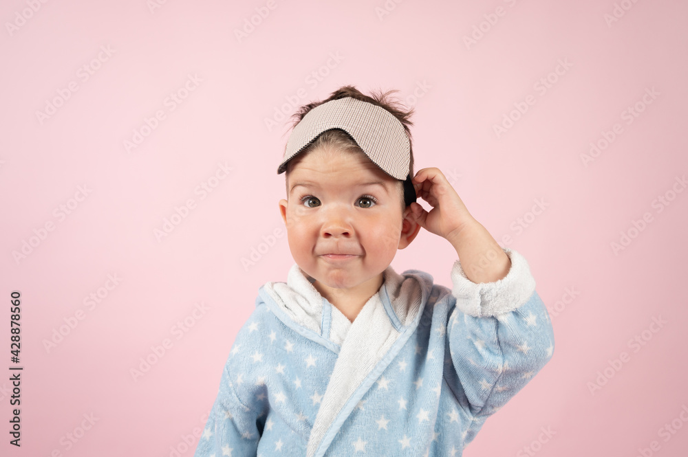 Funny baby boy in bathrobe wearing sleeping mask on pink background. Time to sleep concept Funny baby boy in bathrobe wearing sleeping mask on pink background. Time to sleep concept