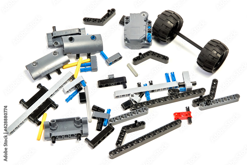 Plastic parts of the constructor, connecting elements and wheels for assembling movable models on a white background, floating focus. Plastic parts of the constructor, connecting elements and wheels for assembling movable models on a white background, floating focus.