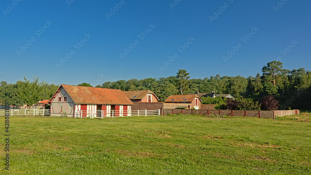 Horse stables in traditional brick stone style and meadows on a sunny day in Oise region, France, high angle view Horse stables in traditional brick stone style and meadows on a sunny day in Oise region, France, high angle view