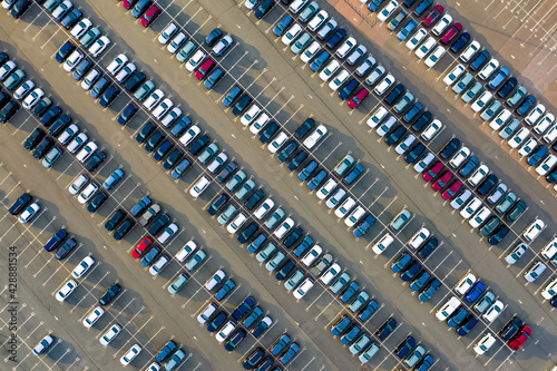 Aerial top down view of the dealership or customs terminal parking lot with a rows of new cars