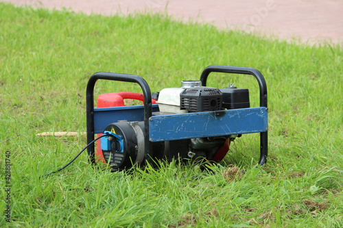 blue and red small power generator stands near a street stage on the grass during City Day entertainment