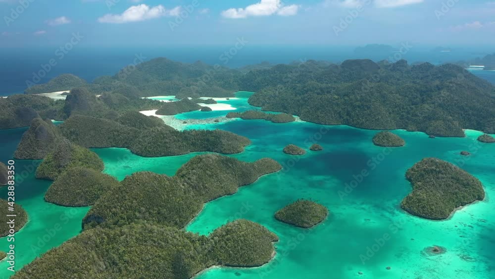 2020 - Excellent aerial shot of the Wayag Islands, Raja Ampat, Indonesia, with the shadows of passing clouds visible in the clear blue water.