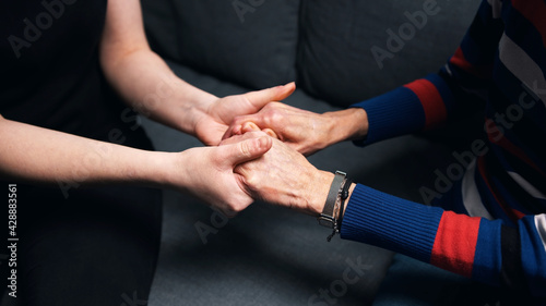 Young person holding hands of an elderly woman. High quality photo