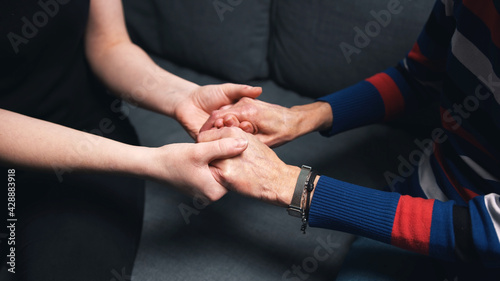 Young person holding hands of an elderly woman. High quality photo