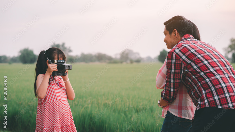 The vintage little daughter take a photo for her parents with a film camera, happily hugging each other