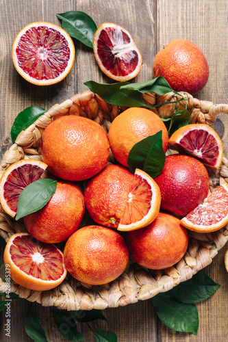 Whole and sliced blood oranges in a basket on wooden table background. Close up  flat lay
