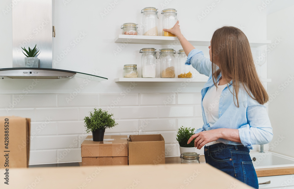 Woman arranges kitchen utensils after moving to new apartment. Woman arranges kitchen utensils after moving to new apartment.