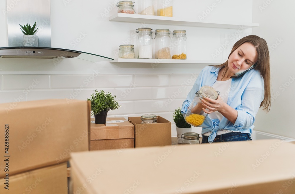 Woman speaking by the phone and arranges kitchen utensils. Woman speaking by the phone and arranges kitchen utensils.