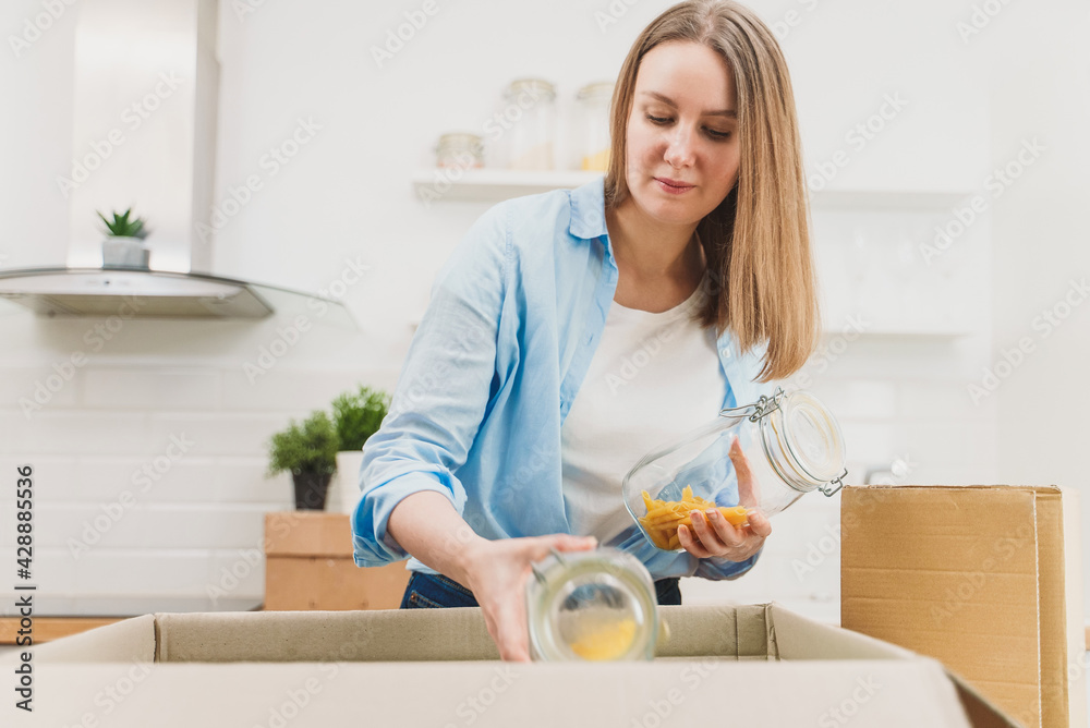 Woman arranges kitchen utensils after moving to new apartment. Woman arranges kitchen utensils after moving to new apartment.