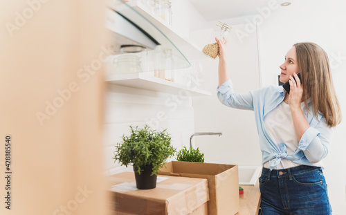 Woman speaking by the phone and arranges kitchen utensils.