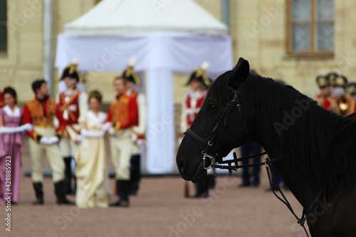 staging a historical scene with the royal family and horse guards on the parade ground in front of the royal palace. The rider and people dressed in royal clothes: ladies and gentlemen