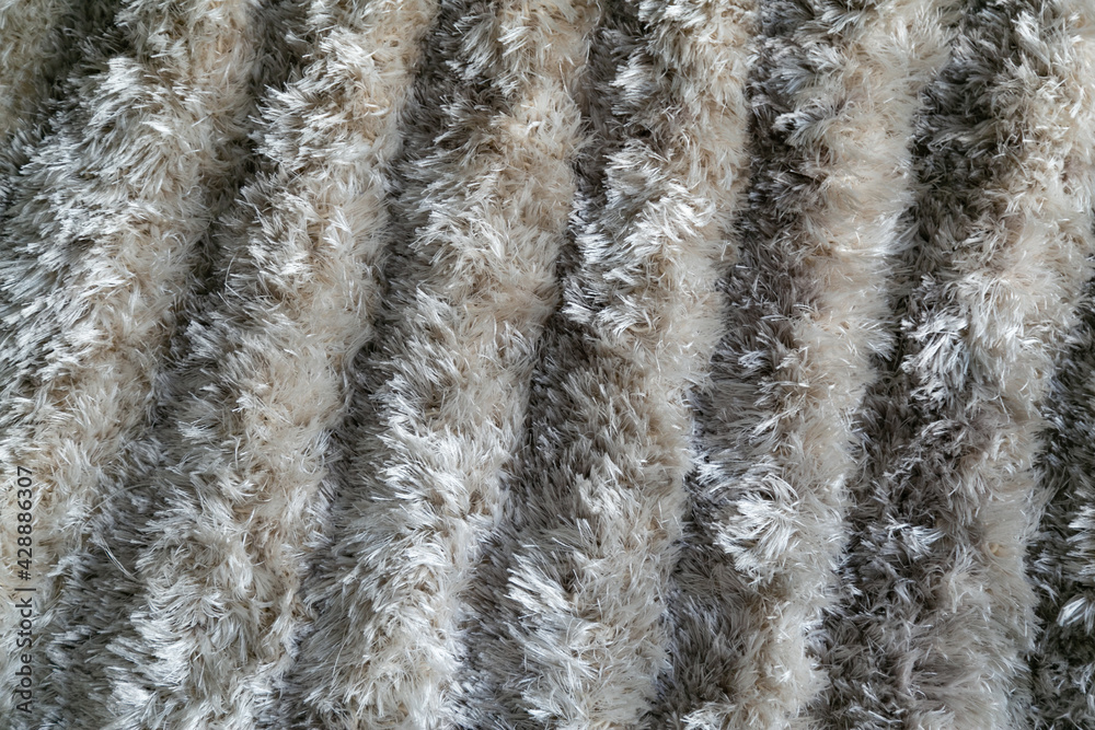 The texture of a long pile of gray artificial carpet. Domestic rug texture. Focus with a shallow depth of field. Polypropylene long pile carpet, close-up. Floor covering made of pvc threads. 