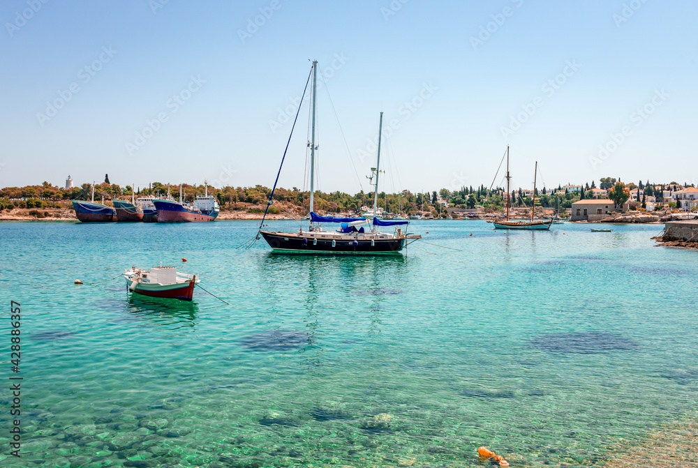 Obraz premium The port and the old shipyard in Spetses, Greece. Spetches is a picturesque small island in Saronic gulf, where superyachts bob up and down next to traditional wooden fishing boats.