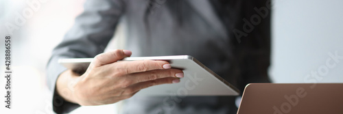 Business woman holding digital tablet and laptop in hands in office closeup