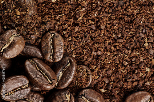 Brown roast, Dark roasts beans coffee on the texture of brown aromatic ground coffee. Macro view background with copyspace.