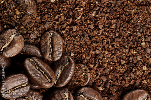 Brown roast, Dark roasts beans coffee on the texture of brown aromatic ground coffee. Macro view background with copyspace. photo