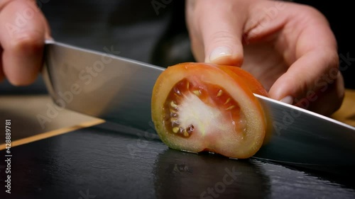 Female hands cut heirloom tomato in slices. Macro shot, 150 fps, slow motion. 