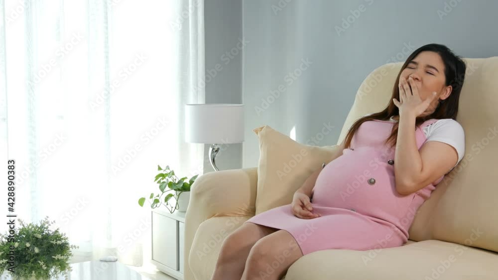 Pregnant woman yawning and sleeping on sofa in the living room Pregnant woman yawning and sleeping on sofa in the living room
