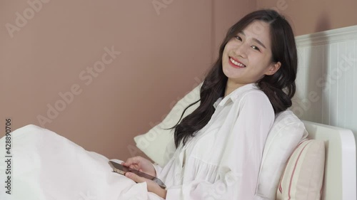 young woman lying on bed and using mobile phone 