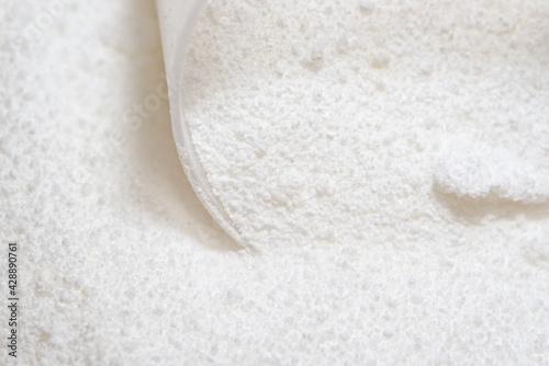 Close up of white powder detergent for laundry, with plastic scoop
