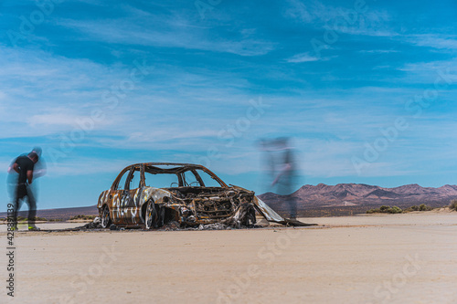 burnt car in desert lake bed with ghosts and graffiti