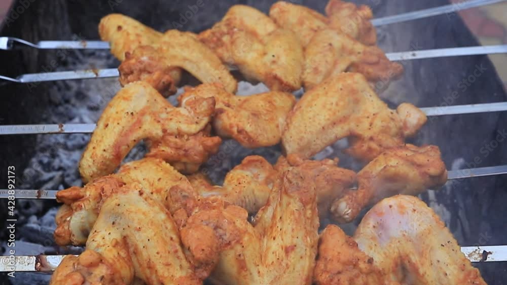 Raw chicken wings on skewers fried on an open fire in the open air Raw chicken wings on skewers fried on an open fire in the open air