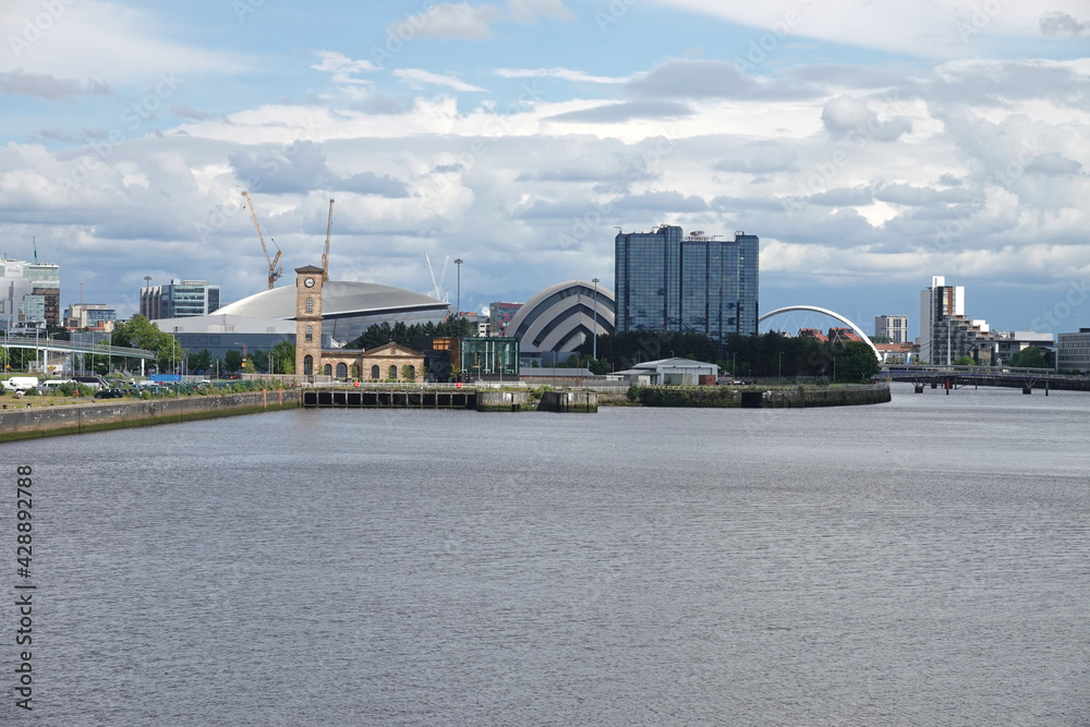 The Glasgow, Scotland West End cityscape from River Clyde is shown from the Partick area during a partly cloudy, afternoon day.