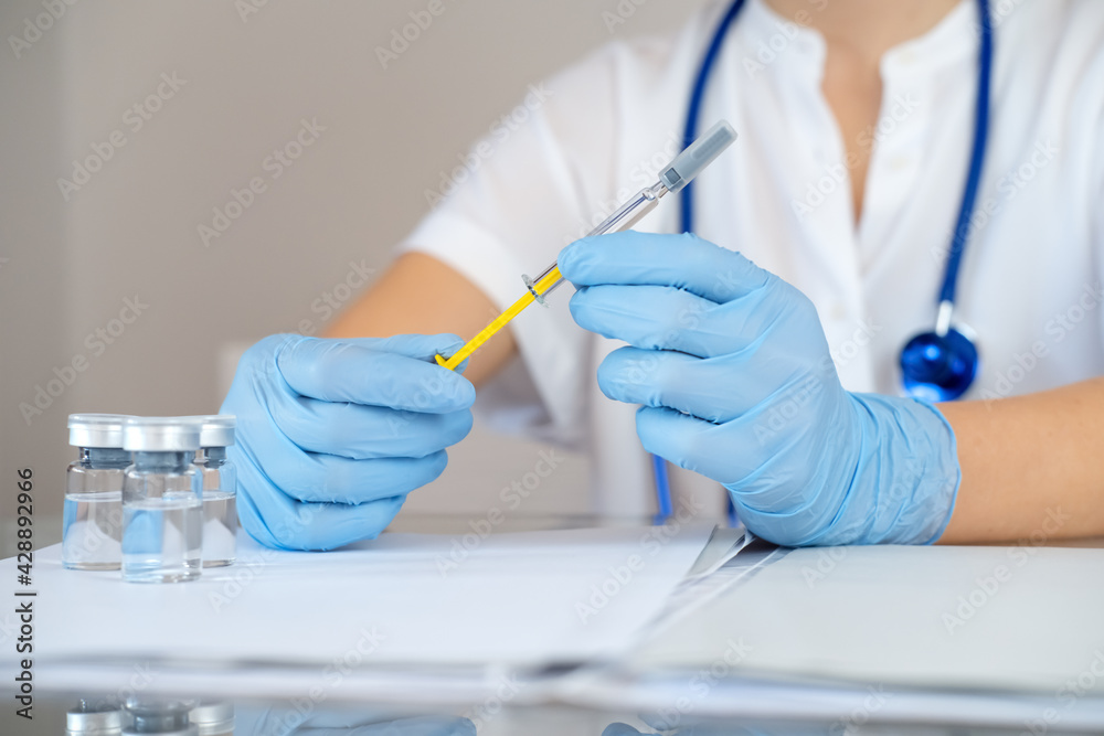 Fototapeta premium Nurse holds syringe with antiviral vaccine during vaccination campaign. Immunization and disease prevention concept. Selective focused. Close up. Unrecognized personality