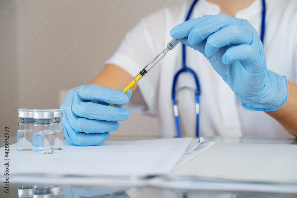 Nurse holds syringe with antiviral vaccine during vaccination campaign. Immunization and disease prevention concept. Selective focused. Close up. Unrecognized personality Nurse holds syringe with antiviral vaccine during vaccination campaign. Immunization and disease prevention concept. Selective focused. Close up. Unrecognized personality