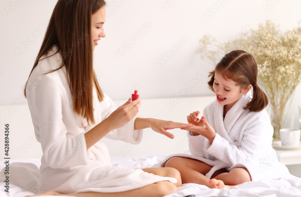 Woman and girl doing manicure on bed