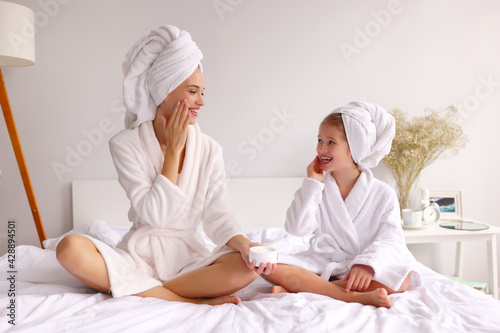 Happy woman and girl applying cream in morning