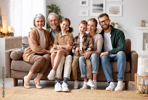 Fotografie Beautiful multi generational family sitting together on couch at home and smilin
