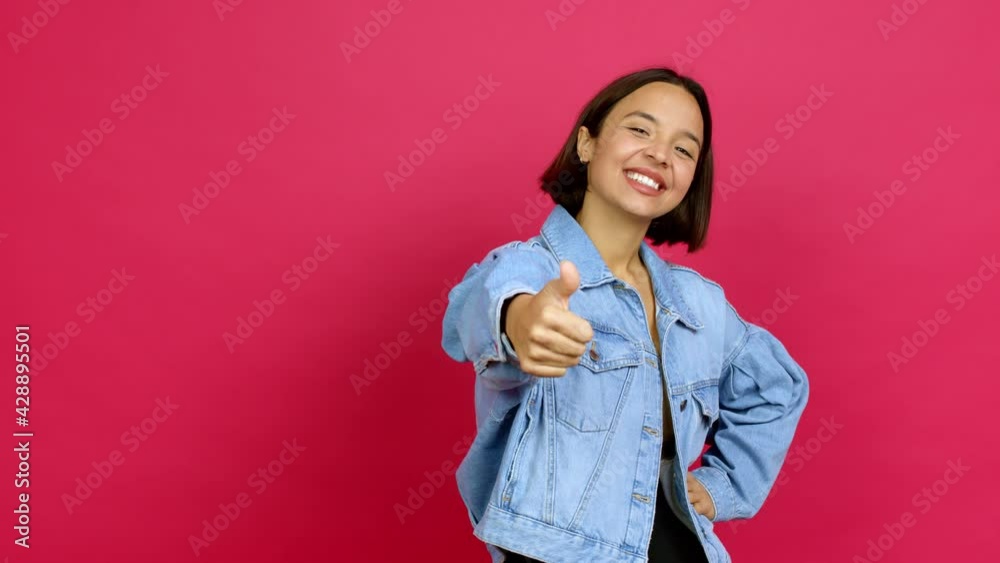 Young latin woman giving thumbs up and smiling because something good has happened over isolated background Young latin woman giving thumbs up and smiling because something good has happened over isolated background