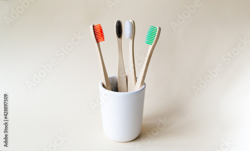 Four multi-colored bamboo toothbrushes in a ceramic glass. Eco friendly stuff concept. Copy space. Horizontal orientation.