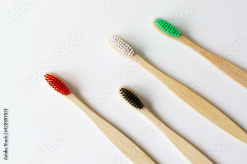 Four multi-colored bamboo toothbrushes  lie on a pastel background. Eco friendly stuff concept. Copy space. Horizontal orientation. Top view.