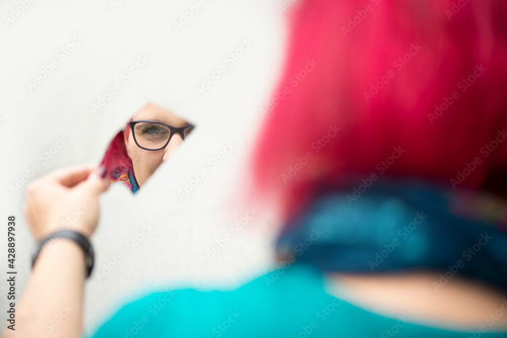 Fototapeta premium Frau mit roten Haaren spiegelt sich in einer Spiegelscherbe