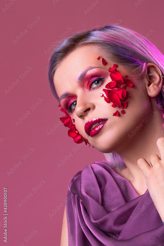stylish and bright young woman with colored makeup and flower petals on her face