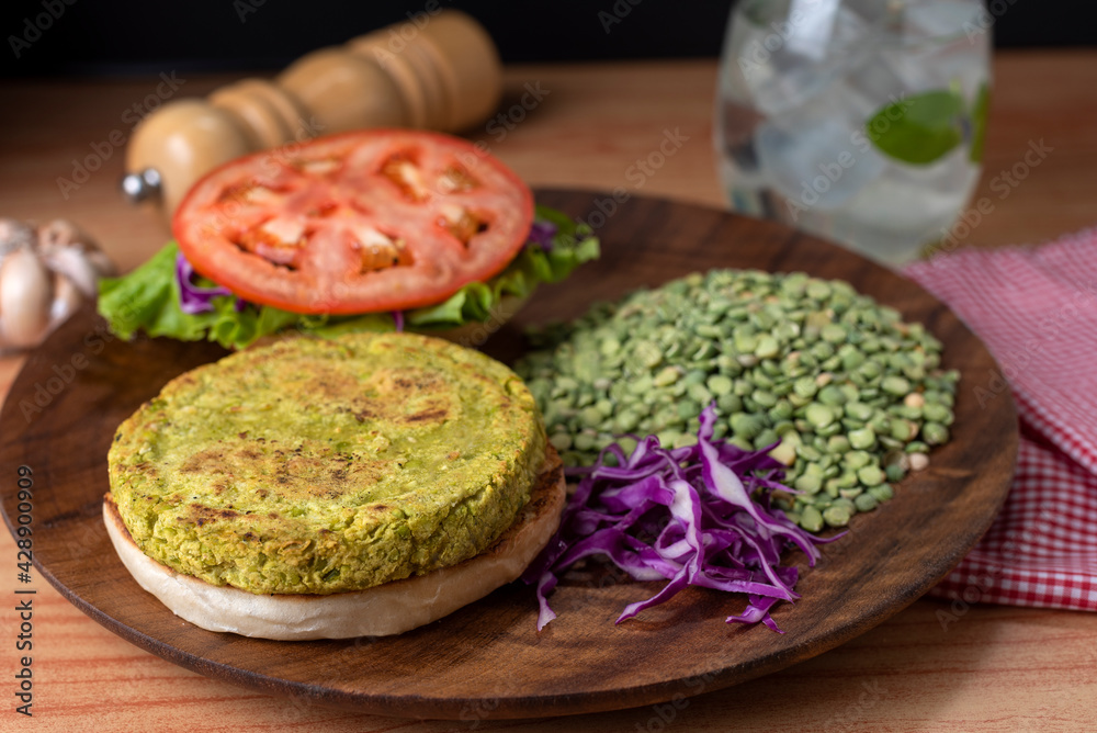 Homemade vegan and vegetarian hamburgers of legumes and vegetables with potatoes lettuce tomato on wooden plate for a healthy diet and life