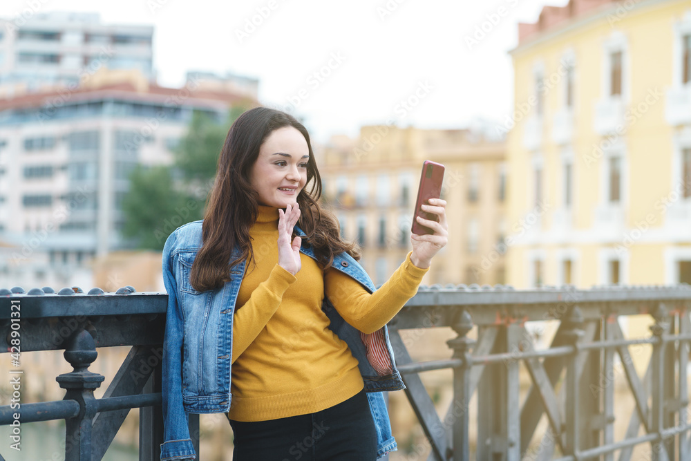 Young woman making a video call on a street at sunset