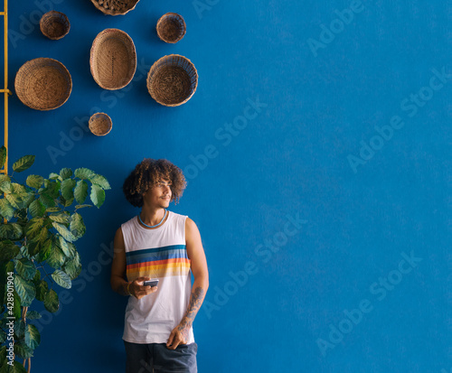 Portrait of handsome afro man using his mobile on a blue background. Copy space.