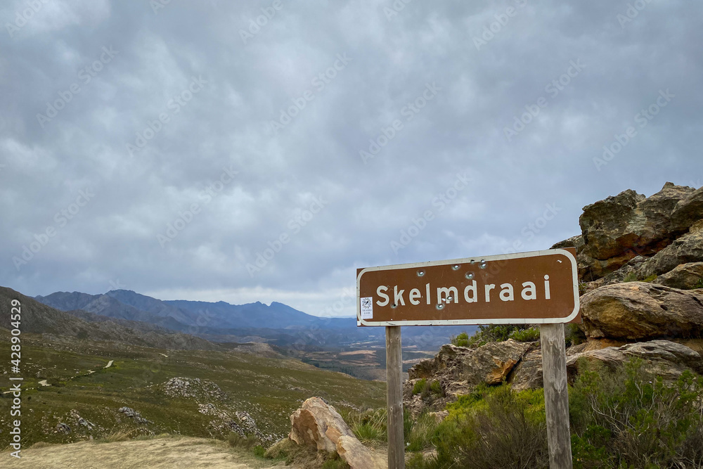 Skelmdraai (sly corner) sign with bullet holes at Swartberg Pass (black mountain pass), South Africa
