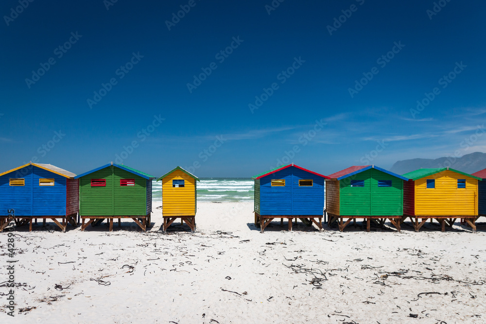 Famous colorful beach houses in Muizenberg near Cape Town, South Africa with mountains of Cape of Good Hope Peninsula in the background. Famous colorful beach houses in Muizenberg near Cape Town, South Africa with mountains of Cape of Good Hope Peninsula in the background.