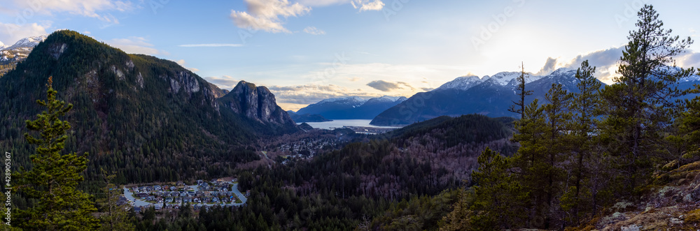 Squamish, North of Vancouver, British Columbia, Canada. Panoramic View from the top of the Mount Crumpit of a small town surrounded by Canadian Mountain Landscape. Spring Sunset